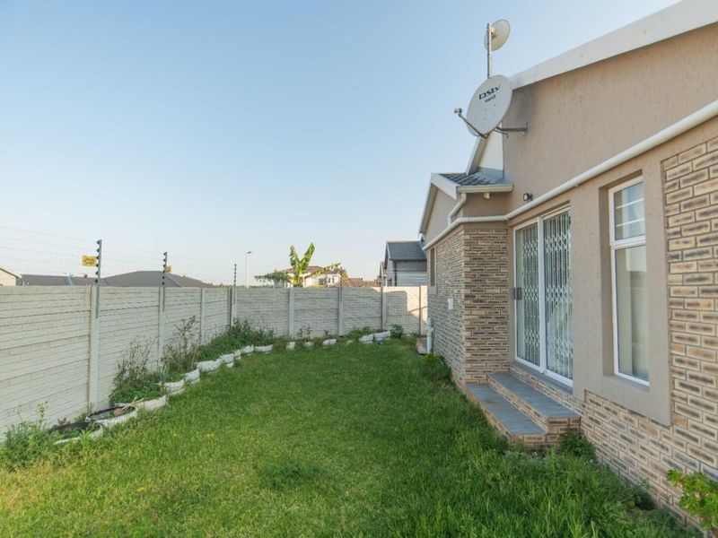 Rear garden area featuring a lawn, precast concrete boundary wall with electric fencing, and access to the home via a sliding glass door.