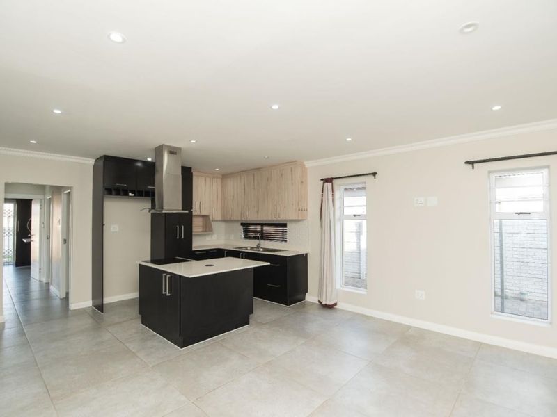 Spacious open-plan kitchen and living area featuring modern two-tone cabinetry, a central island, tiled flooring, and recessed lighting throughout.