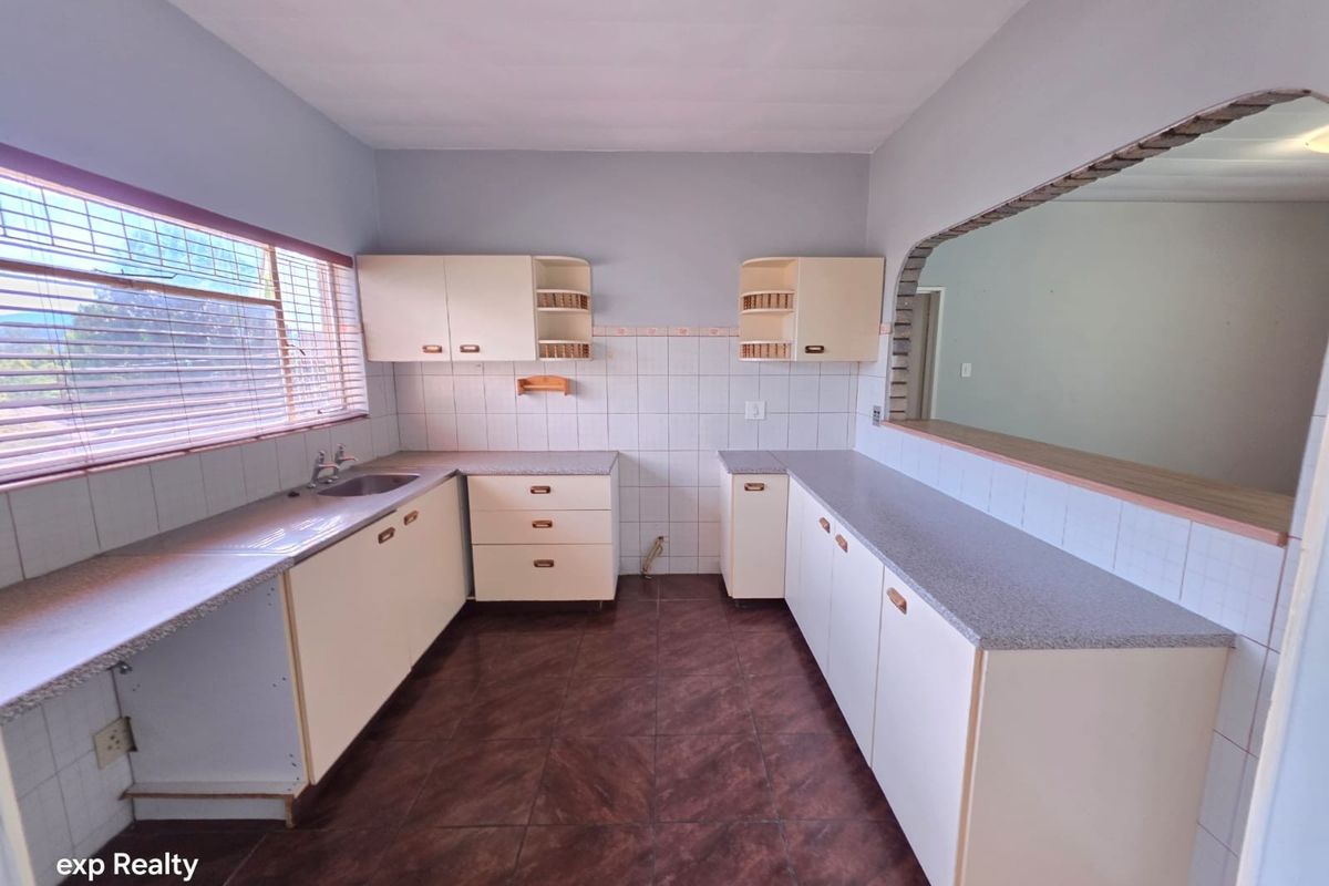 A dated kitchen featuring built-in cabinetry, laminate countertops, and tiled finishes, offering a functional layout ready for modernization.