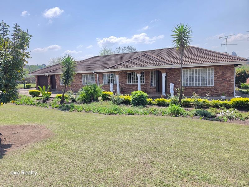 A well-maintained single-story brick home featuring a tiled roof, covered patio with columns, and an expansive front garden.