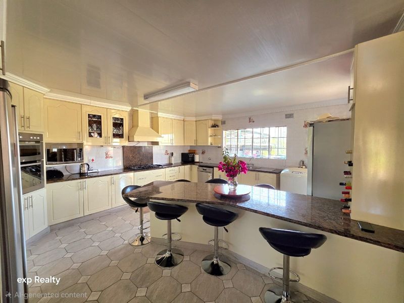 Spacious kitchen featuring cream cabinetry, granite countertops, a central island with breakfast bar seating, and integrated appliances.