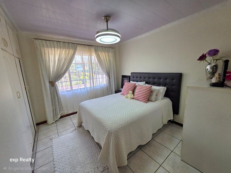 A functional bedroom featuring tiled flooring, built-in cupboards, and a ceiling fan with integrated lighting, providing a comfortable and practical living space.