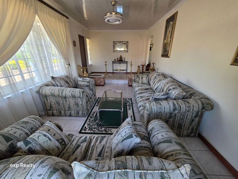 A spacious living room featuring tiled flooring, a central ceiling fan, and coved ceiling details, offering a functional and well-lit living space.