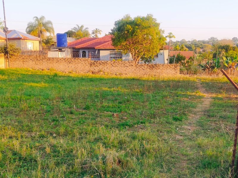 A vacant residential plot featuring perimeter walling and existing fencing, situated in a developed neighborhood setting.