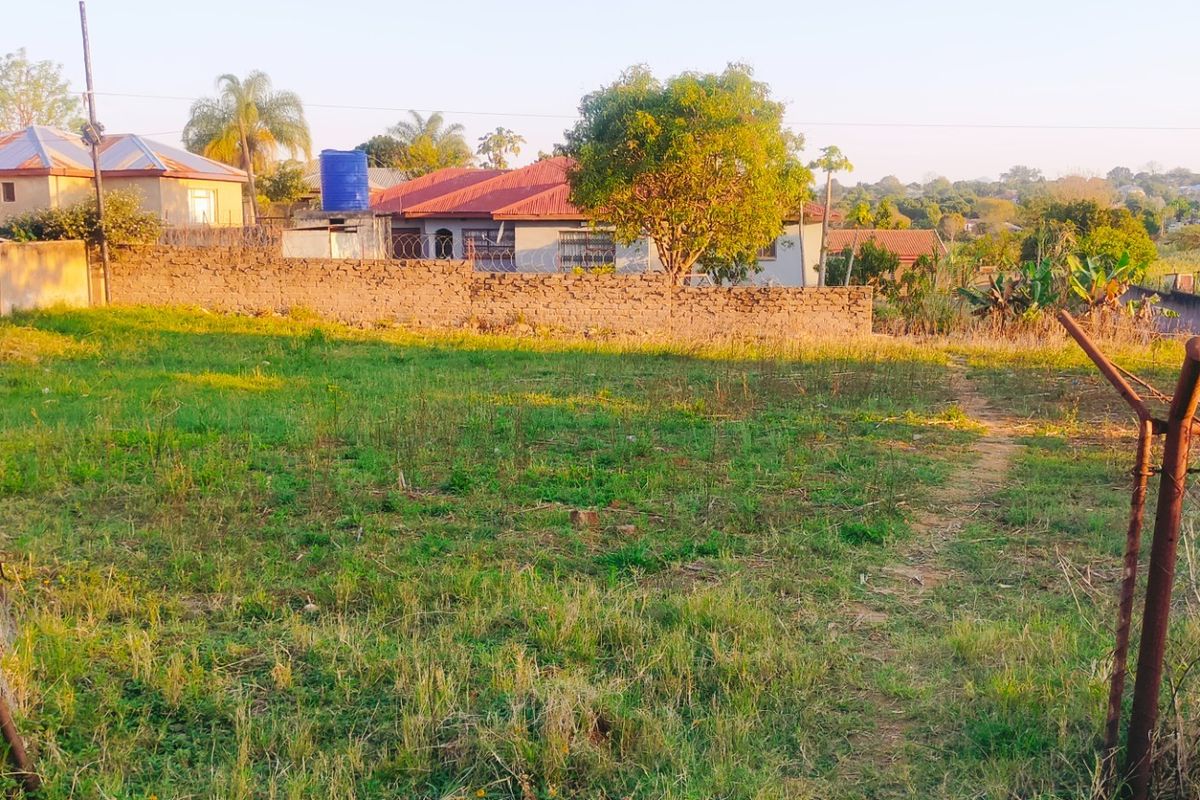 A vacant residential plot featuring perimeter walling and existing fencing, situated in a developed neighborhood setting.