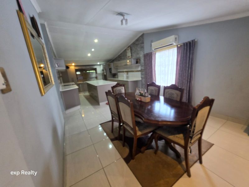 Open-plan living and dining area featuring a modern kitchen with a central island, tiled flooring, and split-system air conditioning.