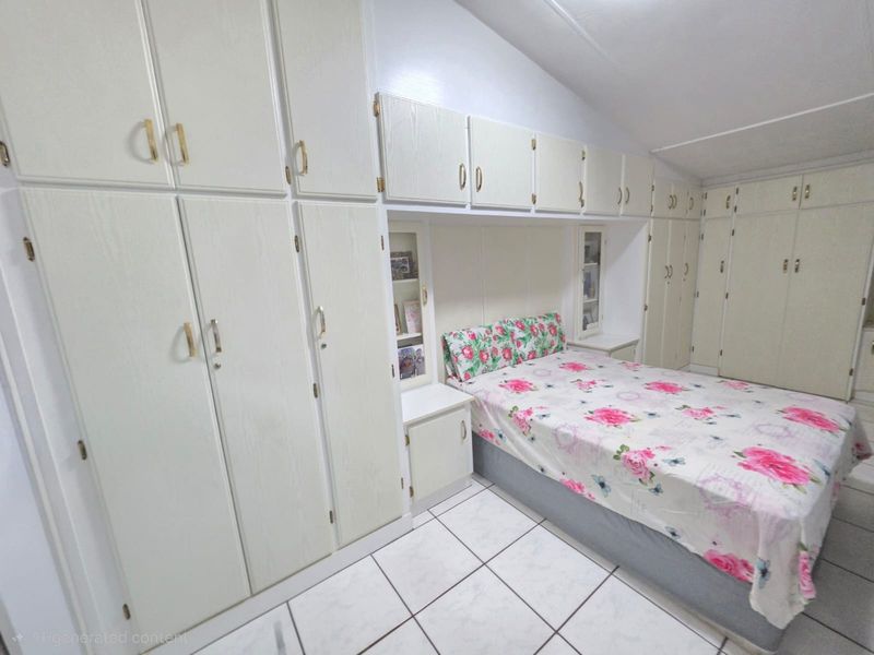Bedroom featuring extensive built-in cabinetry and storage units surrounding the bed area, finished with light-colored tiled flooring.