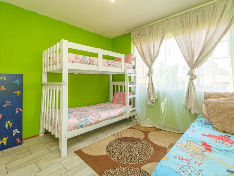 A bedroom featuring tiled flooring and a large window, providing natural light to the space.