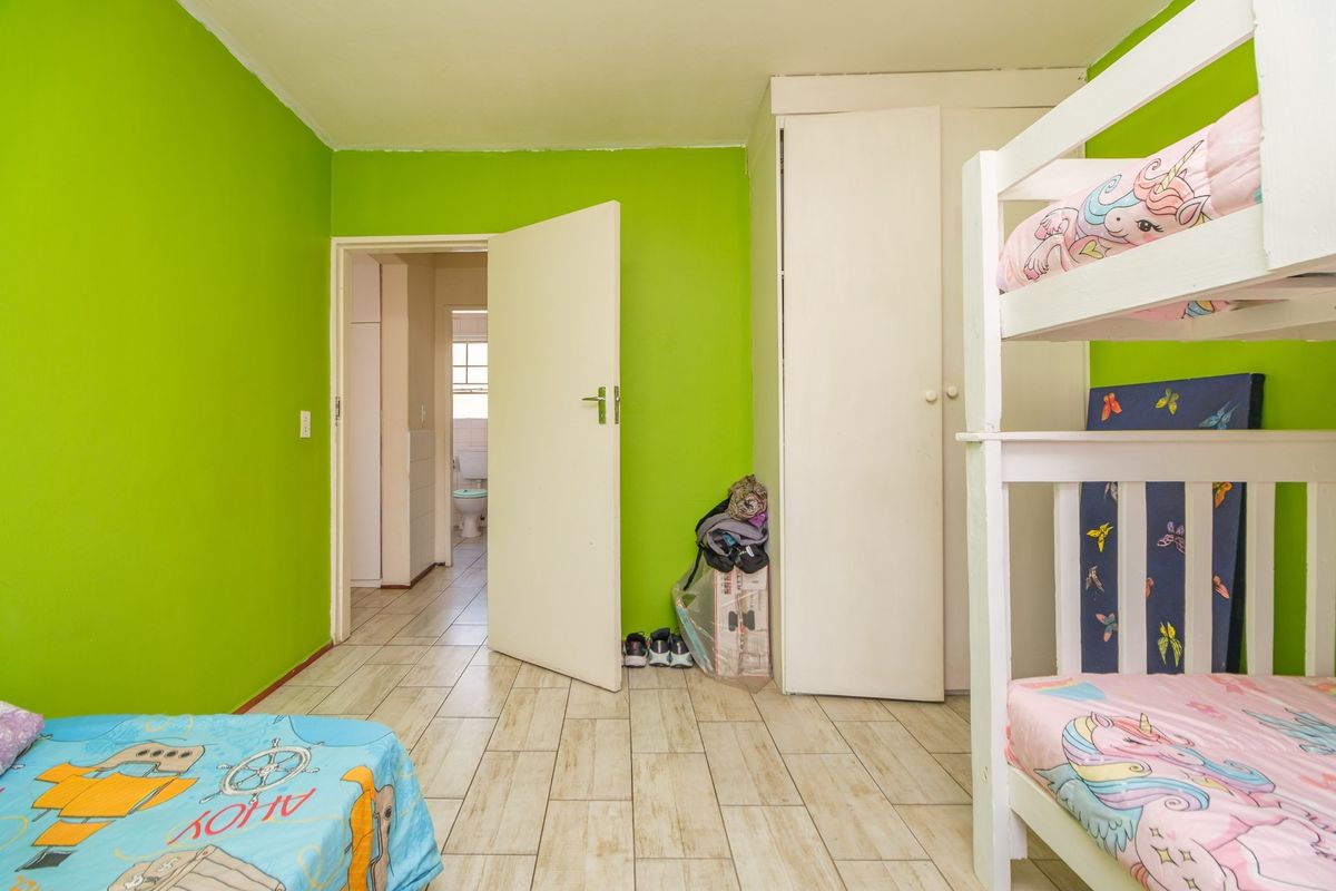 A bedroom featuring tiled flooring and a built-in wardrobe, with direct access to an adjacent bathroom.