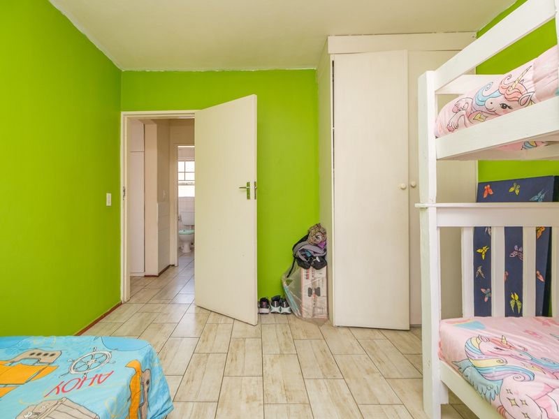 A bedroom featuring tiled flooring and a built-in wardrobe, with direct access to an adjacent bathroom.