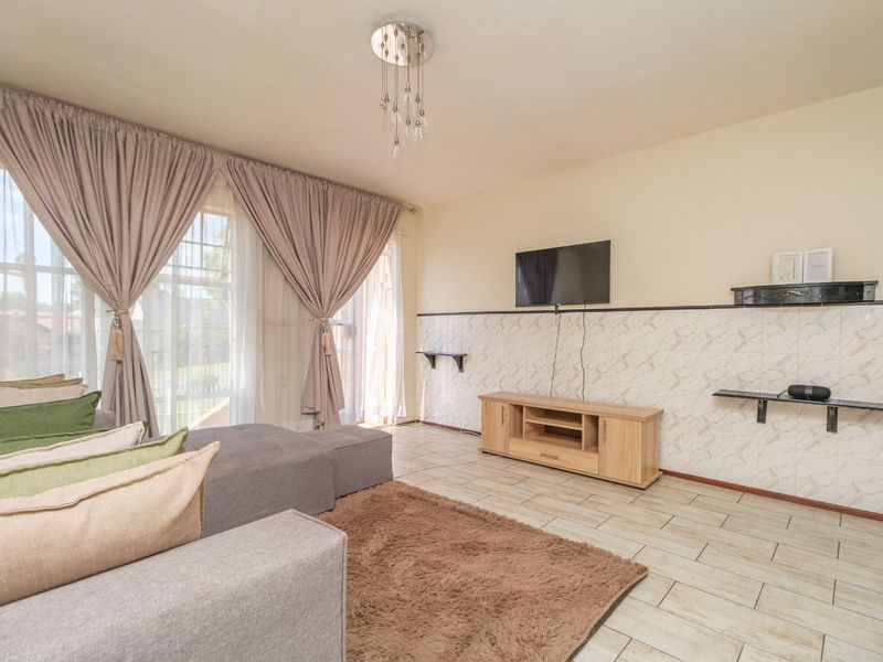 A living room featuring tiled flooring, decorative wall tiling, and a sliding glass door providing natural light.