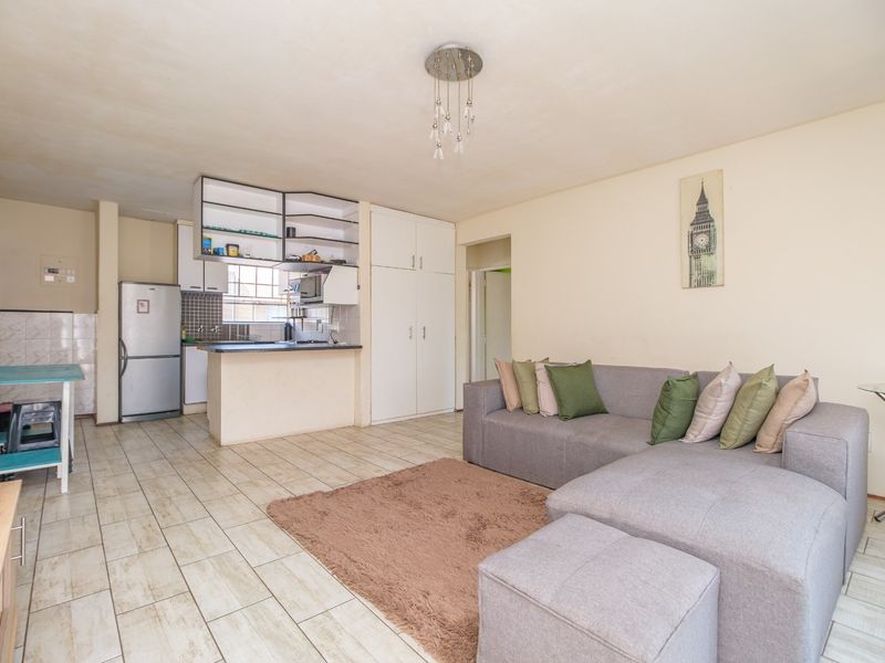 Open-plan living and kitchen area featuring tiled flooring, built-in cabinetry, and ample storage space, offering a functional layout for modern apartment living.