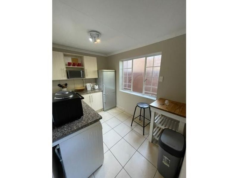 A functional kitchen featuring built-in cabinetry, granite countertops, and tiled flooring, providing a practical workspace with natural light from the window.