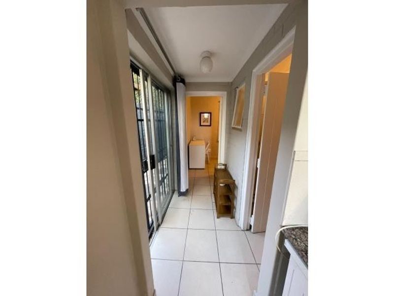 A tiled hallway featuring a sliding glass door providing access to the exterior and connecting to adjacent rooms.