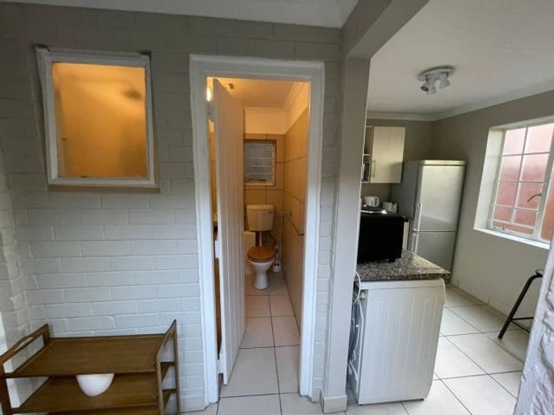 A functional kitchen area featuring tiled floors, built-in cabinetry with granite countertops, and direct access to an adjoining bathroom.