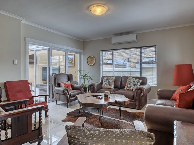A well-maintained living room featuring tiled flooring, a split-system air conditioner, and large sliding glass doors providing access to an outdoor patio area.