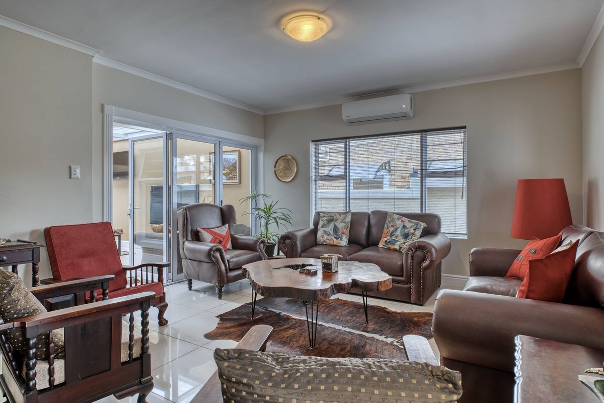 A well-maintained living room featuring tiled flooring, a split-system air conditioner, and large sliding glass doors providing access to an outdoor patio area.