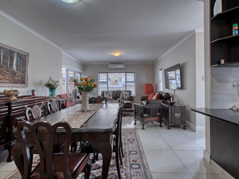 Spacious open-plan living and dining area featuring neutral walls, tiled flooring, and a split-system air conditioner, with direct access to the outdoor space.