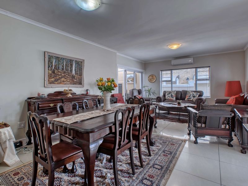 Spacious open-plan living and dining area featuring large format floor tiles, split-system air conditioning, and direct access to an outdoor patio area.