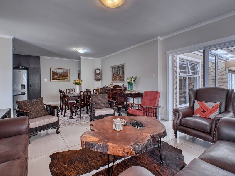 Spacious open-plan living and dining area featuring neutral tiled flooring, coved cornicing, and large sliding glass doors providing access to the patio.