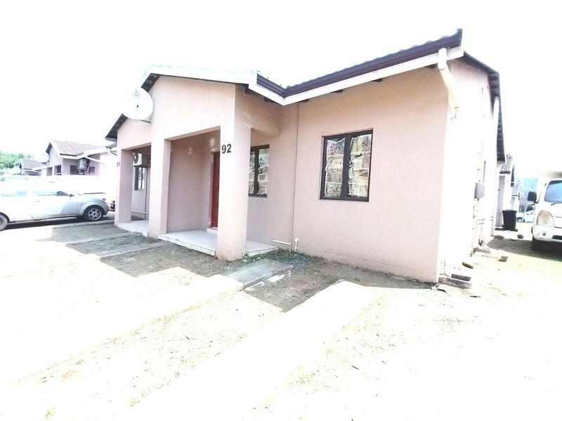 Front elevation of a single-story residential house featuring a covered entrance, tiled roof, and concrete driveway access.