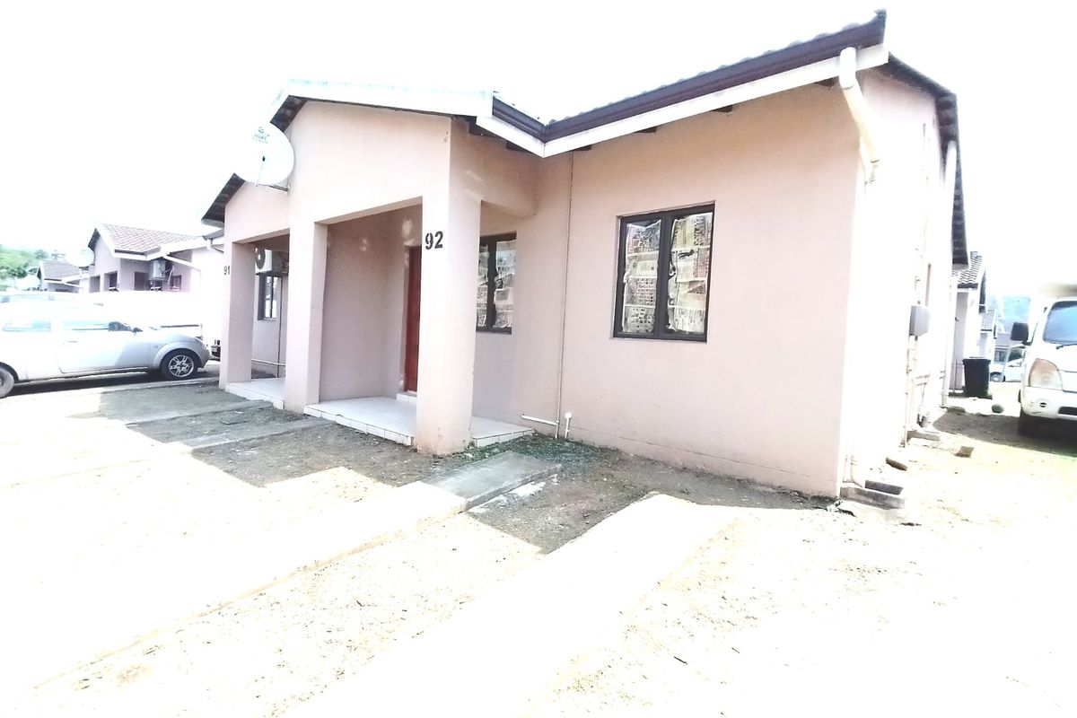 Front elevation of a single-story residential house featuring a covered entrance, tiled roof, and concrete driveway access.