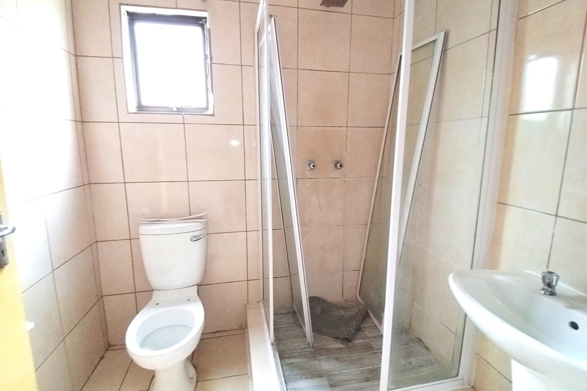 A functional bathroom featuring a pedestal basin, toilet, and a shower enclosure with tiled finishes throughout.