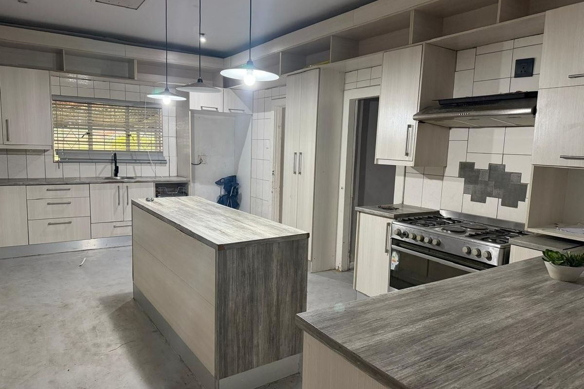 Spacious kitchen featuring built-in cabinetry, a central island, and a gas stove, currently awaiting final flooring installation and finishing touches.