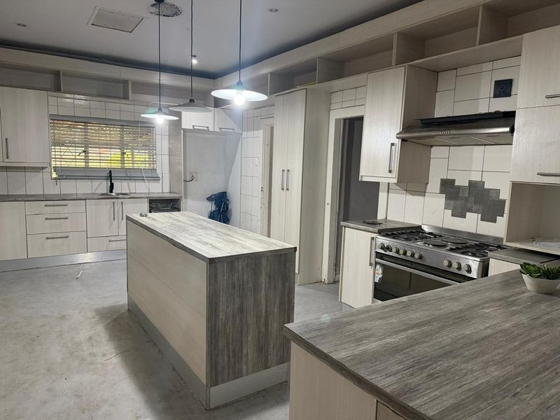 Spacious kitchen featuring built-in cabinetry, a central island, and a gas stove, currently awaiting final flooring installation and finishing touches.