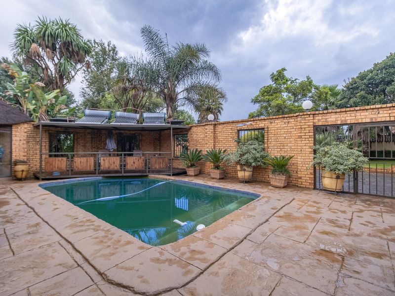 Outdoor pool area featuring a paved deck, brick boundary wall, and integrated solar water heating panels on the adjacent structure.