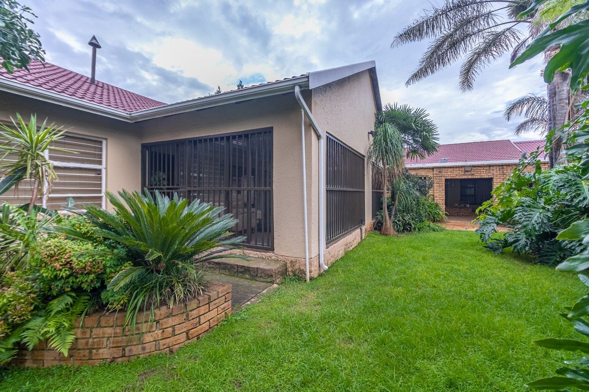 Rear view of the farm property featuring a landscaped garden, brick planter, and secure sliding door access to the main dwelling.