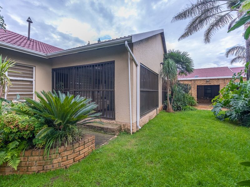 Rear view of the farm property featuring a landscaped garden, brick planter, and secure sliding door access to the main dwelling.