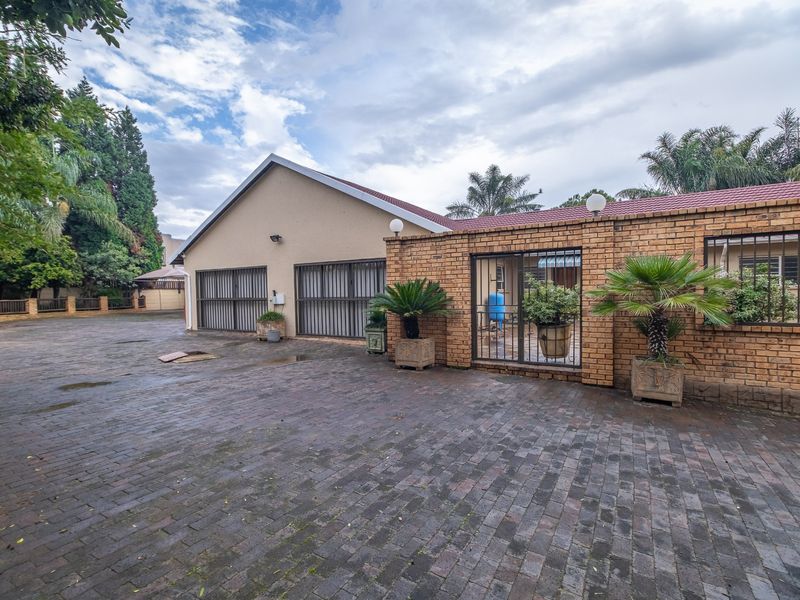 Front exterior view of the property featuring extensive brick paving, secure gated access, and a tiled roof structure.