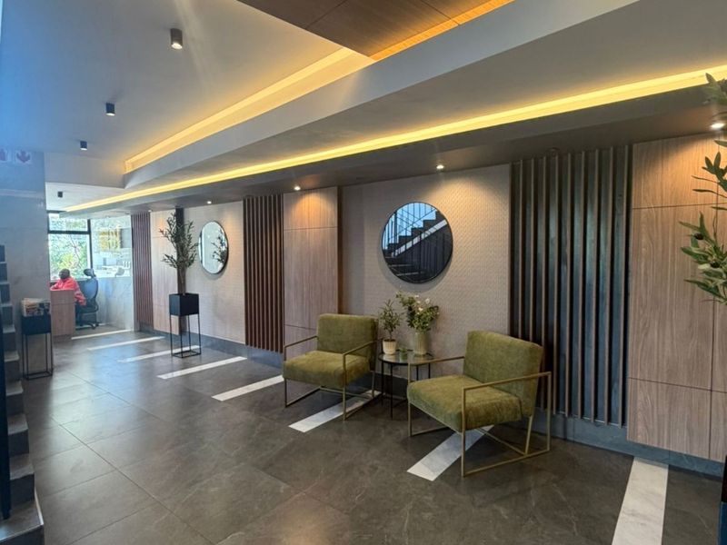 Modern apartment entrance lobby featuring high-end wood paneling, sophisticated cove lighting, and premium tiled flooring.