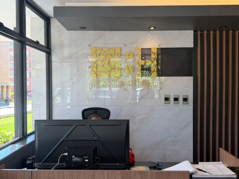 Modern reception area featuring a professional desk, marble-look wall cladding, timber slat accents, and large windows providing ample natural light.