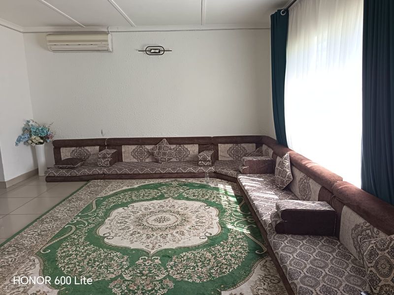 A living room featuring tiled flooring and a wall-mounted split-system air conditioner.