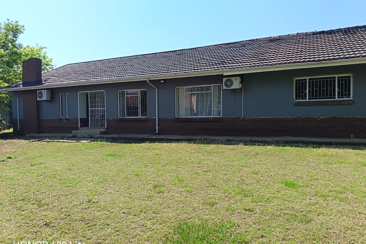 Rear view of the house featuring a tiled roof, brick chimney, security bars on windows, and an installed air conditioning unit.
