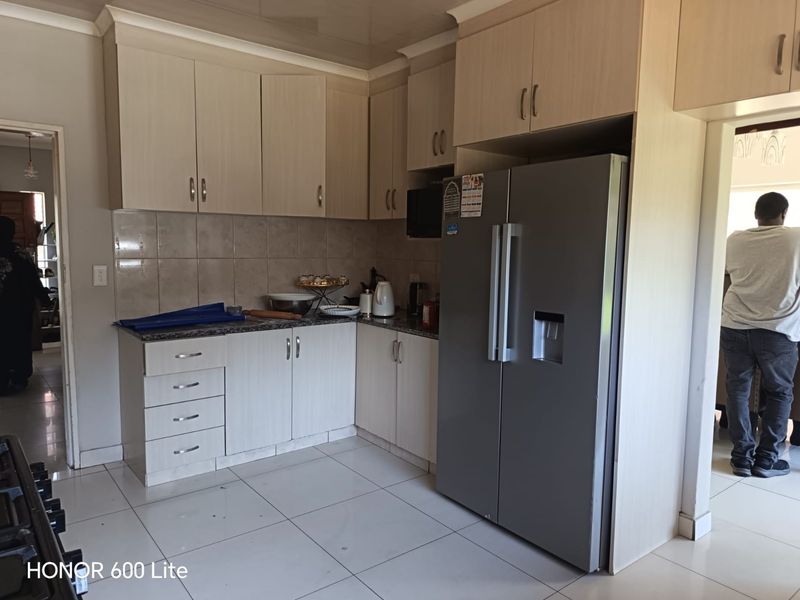 A functional kitchen featuring light-toned laminate cabinetry, granite countertops, a tiled backsplash, and tiled flooring, providing a clean and practical workspace.