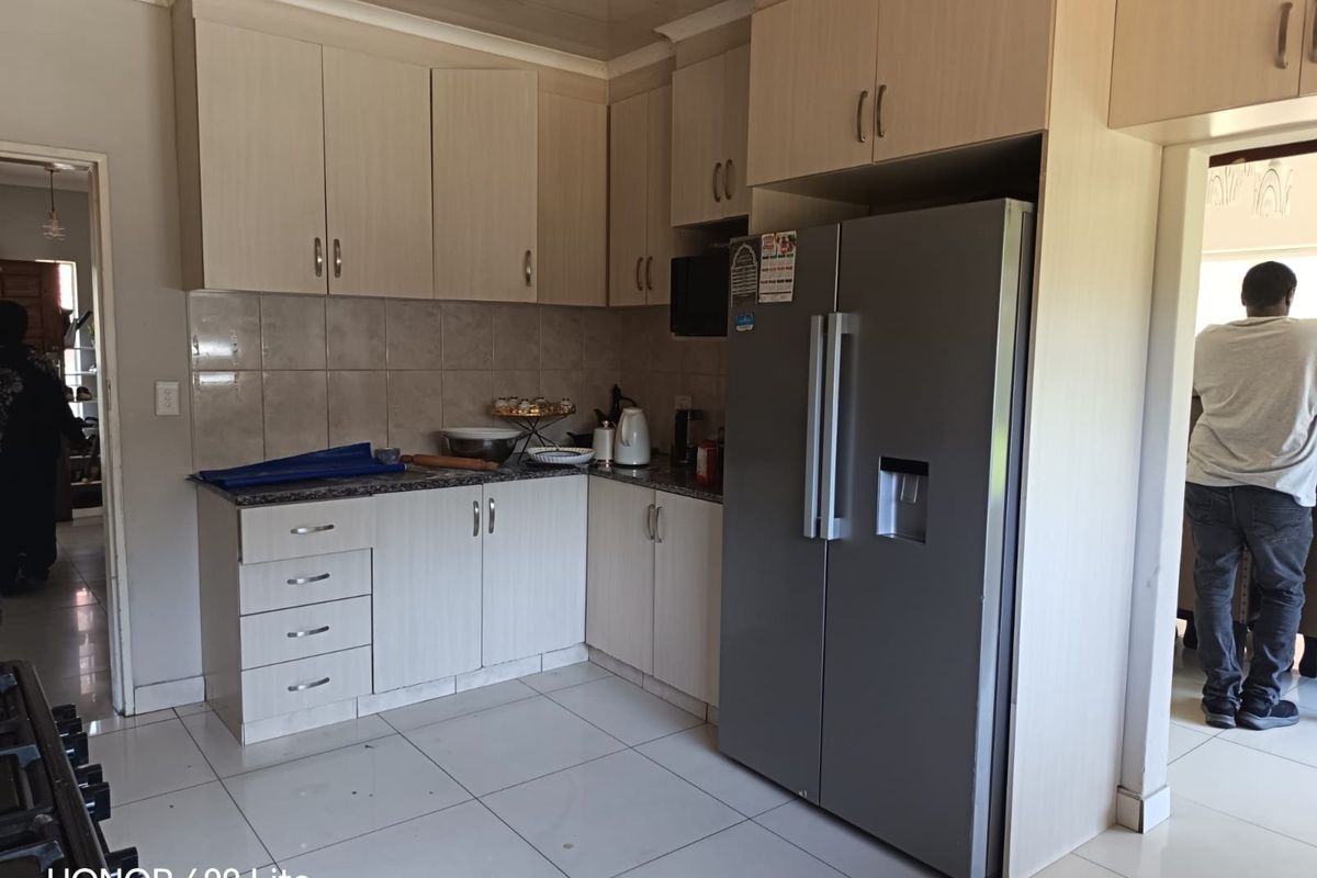 A functional kitchen featuring light-toned laminate cabinetry, granite countertops, a tiled backsplash, and tiled flooring, providing a clean and practical workspace.