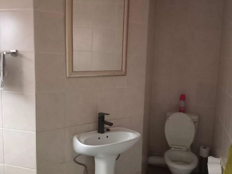 A functional bathroom featuring a pedestal basin, toilet, and neutral wall tiling, providing a clean and practical space.