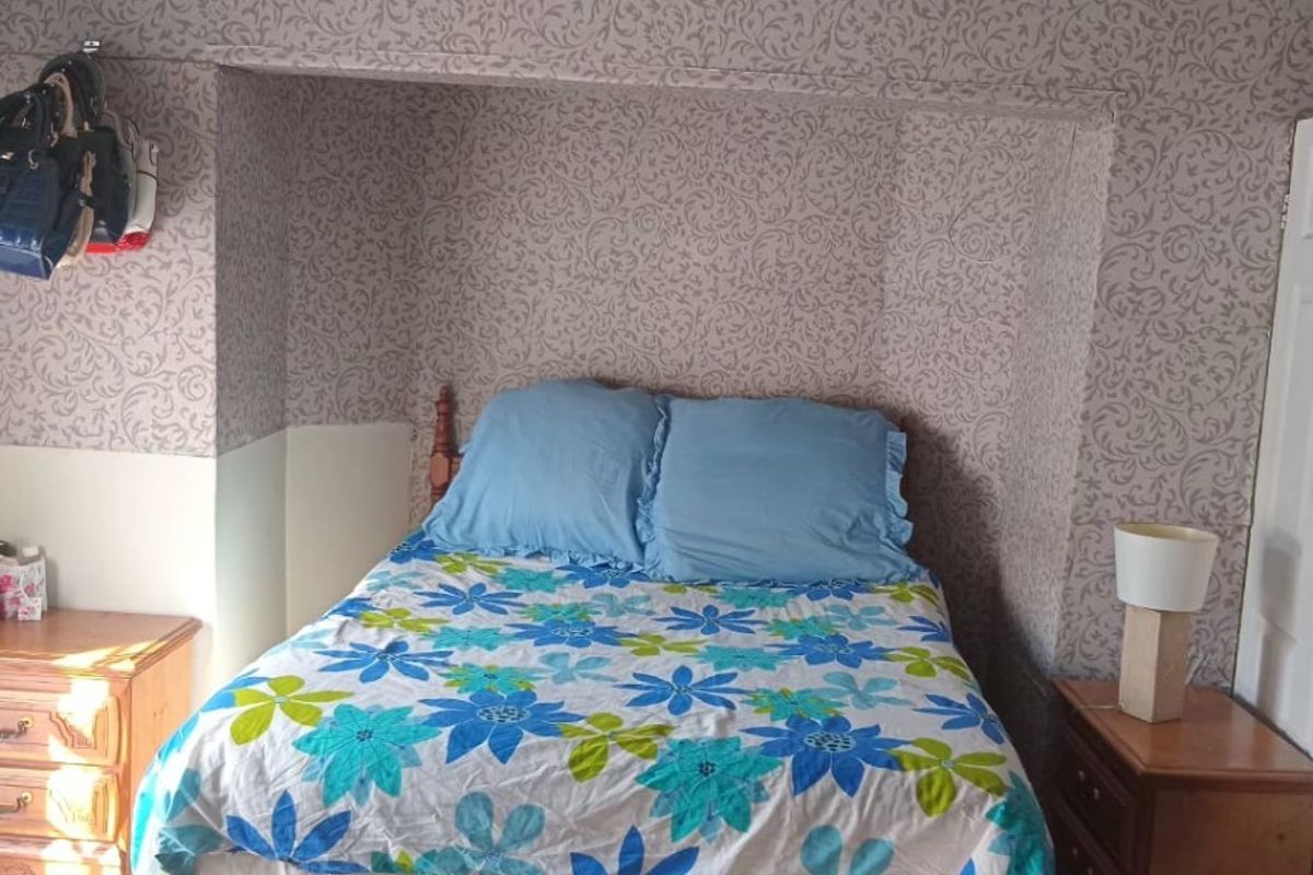 A bedroom featuring tiled flooring and a recessed alcove area with patterned wallpaper.