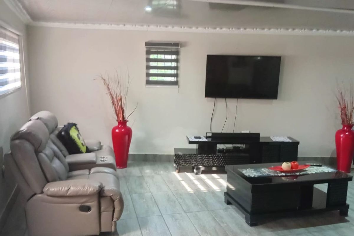 A living room featuring tiled flooring, coved ceiling details, and roller blinds, providing a functional and neutral space for relaxation.