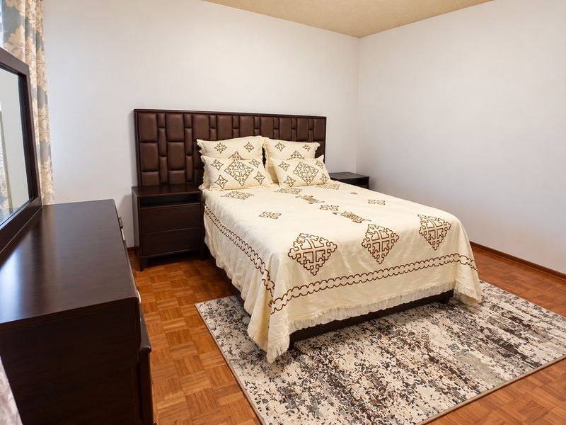 A bedroom featuring classic parquet wood flooring and neutral wall finishes, providing a clean and functional space.