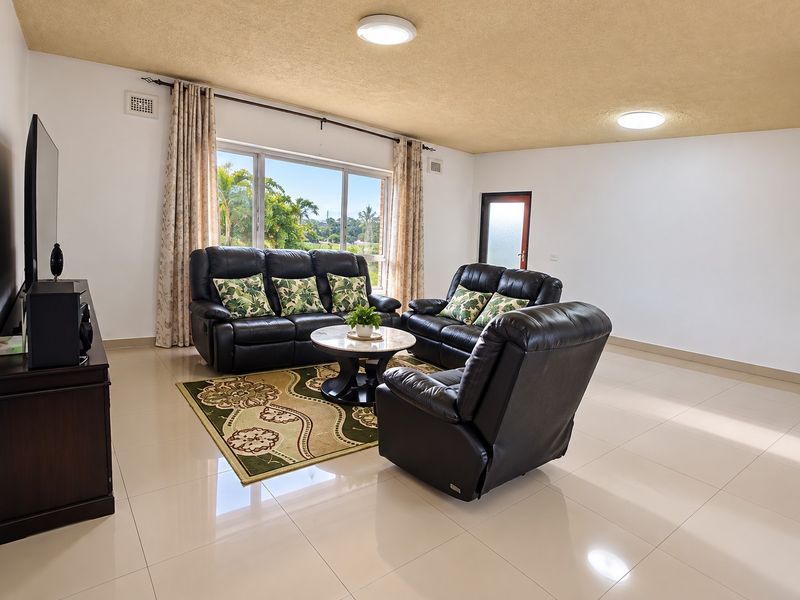 Spacious living room featuring large windows, tiled flooring, and a textured ceiling, offering a bright and open area for relaxation.