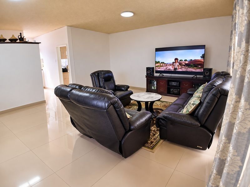 A spacious living room featuring polished tile flooring and a textured ceiling, providing a neutral foundation for comfortable family living.