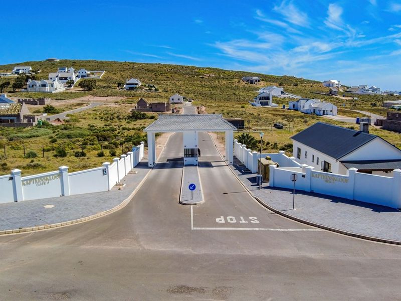 Aerial view of the secure estate entrance gatehouse with paved access roads and perimeter boundary walls.