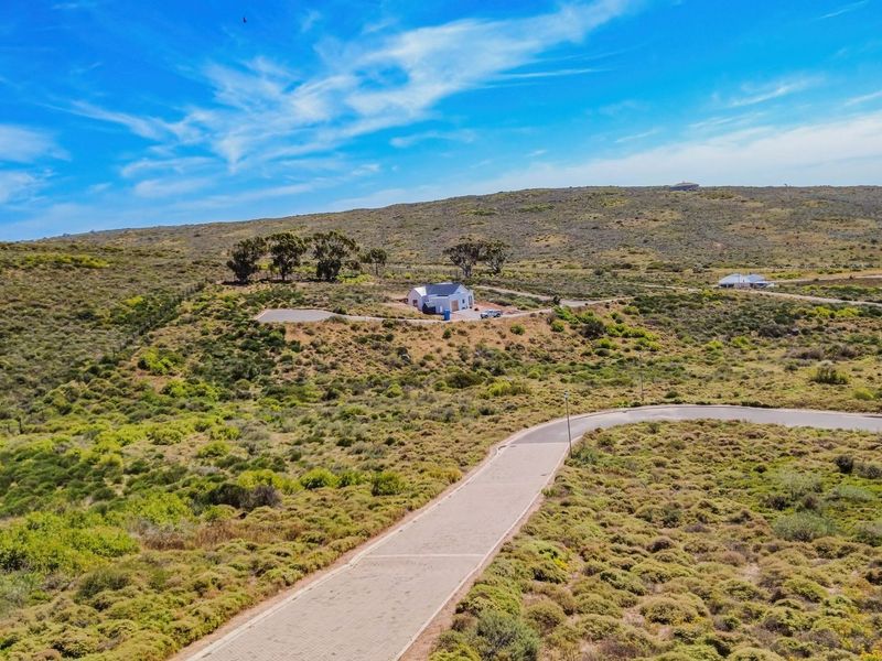 An aerial view of the property showing the surrounding natural landscape and the paved access road leading to the house.