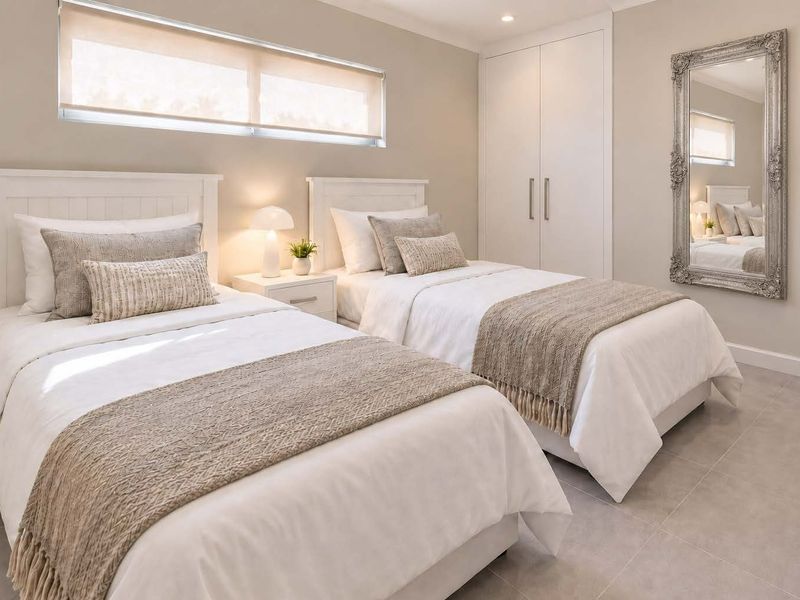 A well-maintained bedroom featuring neutral tones, tiled flooring, built-in wardrobe storage, and a horizontal window with a roller blind.