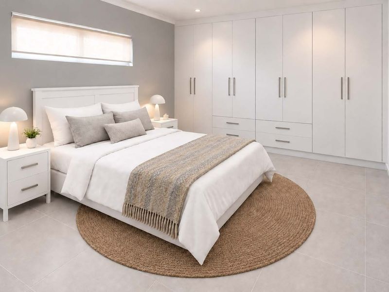 A modern, well-maintained bedroom featuring extensive built-in cabinetry, neutral tiled flooring, and recessed lighting.