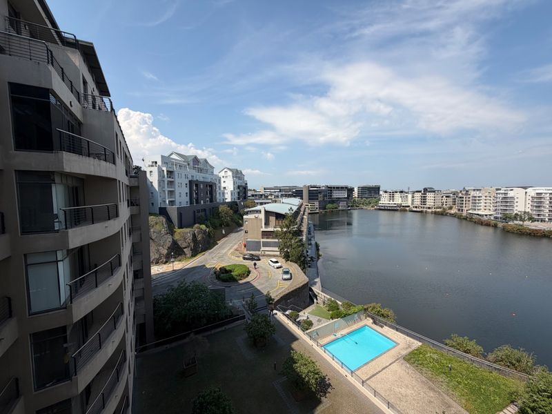 Elevated view overlooking the waterfront, surrounding office and residential buildings, and a communal swimming pool area.